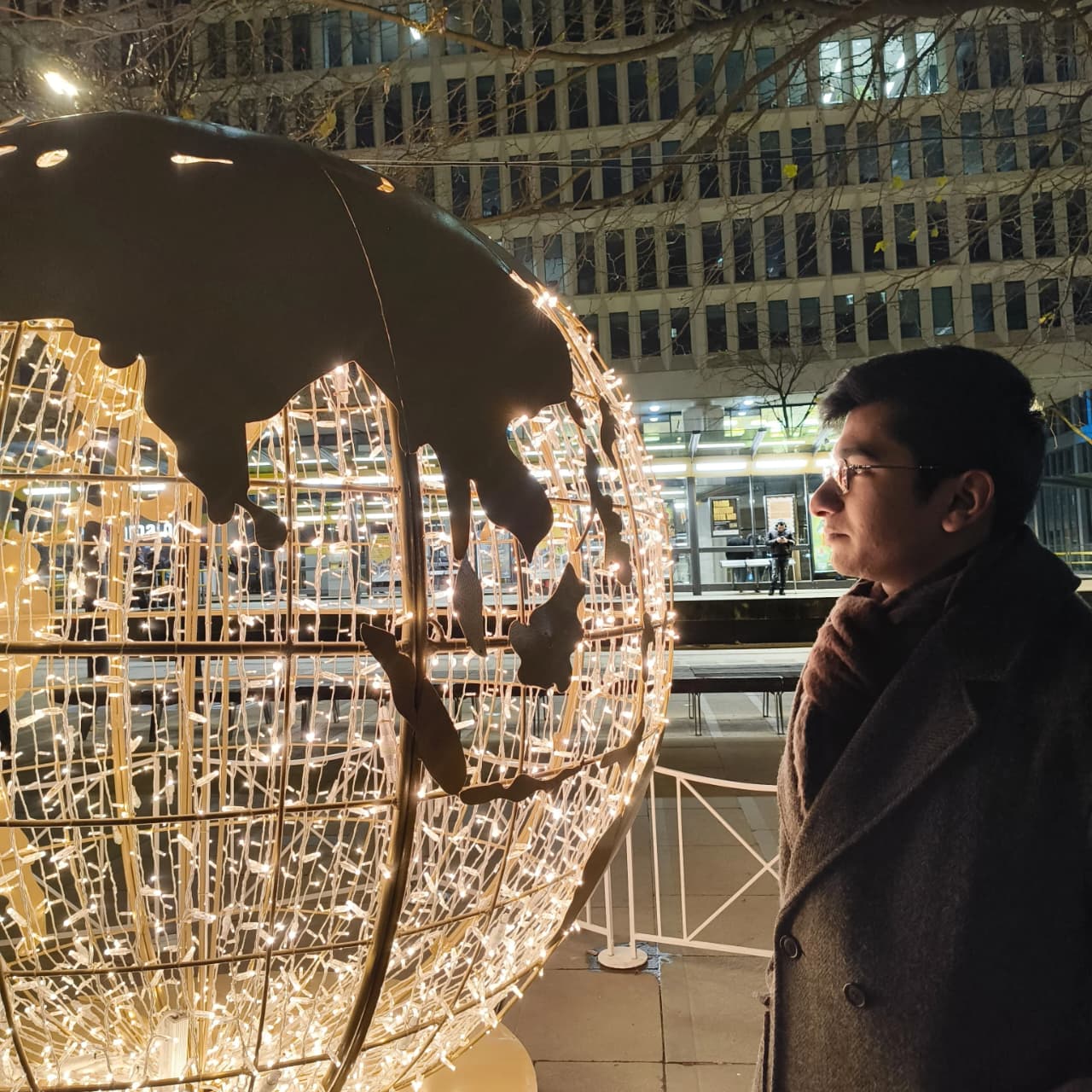 Piyush beside an illuminated globe at the Manchester Christmas lights